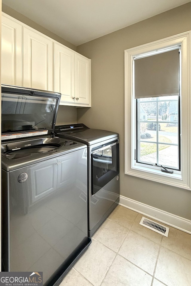 laundry area featuring cabinet space, visible vents, light tile patterned flooring, independent washer and dryer, and baseboards