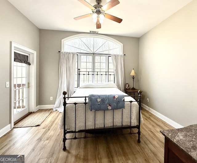 bedroom with access to outside, wood finished floors, visible vents, and baseboards