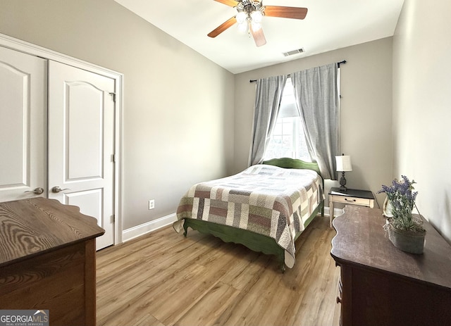 bedroom featuring light wood-type flooring, baseboards, visible vents, and ceiling fan