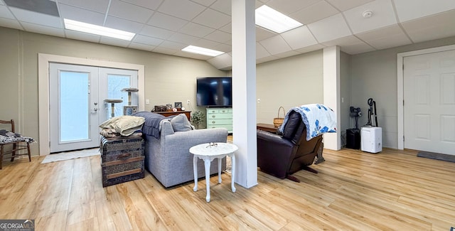 living room featuring a paneled ceiling, french doors, and light wood-style flooring