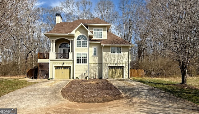 view of side of property featuring a garage, concrete driveway, a chimney, and a balcony