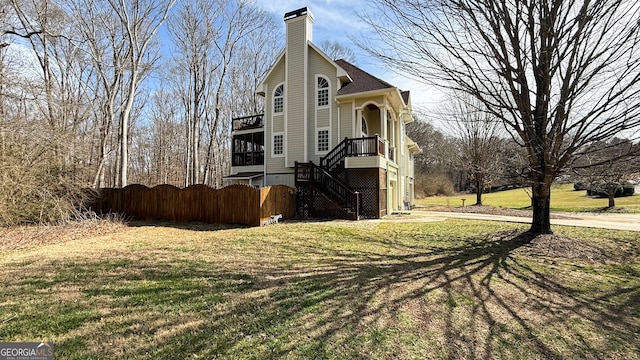 view of front facade featuring a front yard, fence, a chimney, and stairs