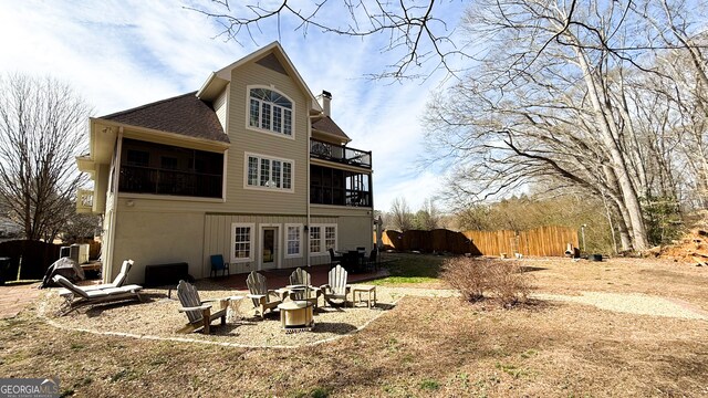 rear view of house with an outdoor fire pit, fence, a sunroom, roof with shingles, and a chimney