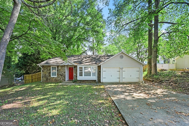 view of front facade featuring an attached garage, fence, stone siding, driveway, and a front yard