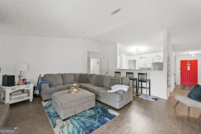 living room with lofted ceiling, a textured ceiling, visible vents, and dark wood-style flooring