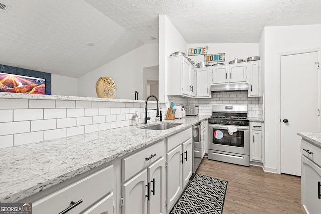 kitchen with gas stove, vaulted ceiling, a sink, light wood-type flooring, and under cabinet range hood