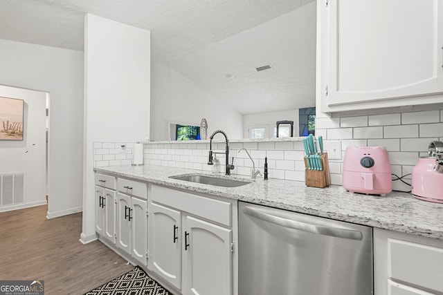 kitchen with a sink, visible vents, dishwasher, and wood finished floors