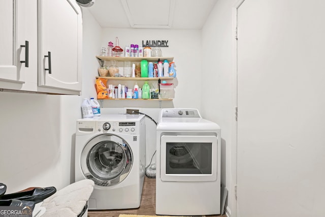 clothes washing area with cabinet space, washer and clothes dryer, and wood finished floors