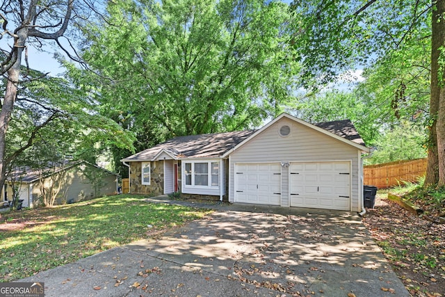 ranch-style home with concrete driveway, fence, a garage, stone siding, and a front lawn