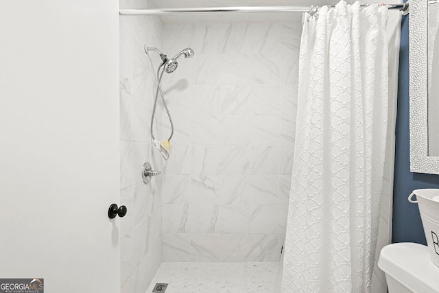 full bathroom featuring tiled shower and toilet