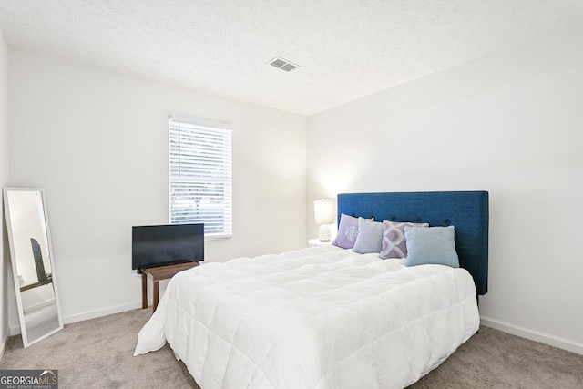 bedroom featuring carpet floors, baseboards, visible vents, and a textured ceiling