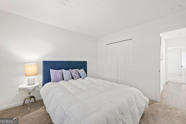 bedroom with a closet, light carpet, visible vents, and baseboards