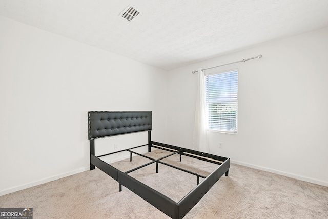 carpeted bedroom with visible vents, a textured ceiling, and baseboards