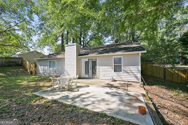 back of property featuring a fenced backyard, a chimney, and a patio