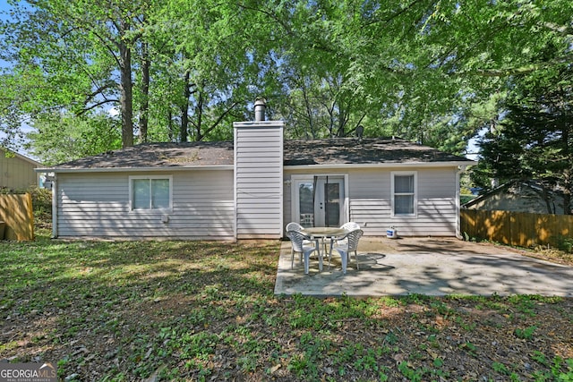 rear view of property with french doors, a yard, a chimney, a patio area, and fence