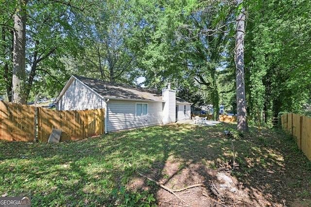 exterior space featuring a fenced backyard, a chimney, and a yard