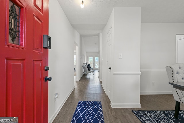 entryway featuring a textured ceiling, wood finished floors, and baseboards