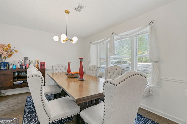 dining room with visible vents, a notable chandelier, baseboards, and wood finished floors