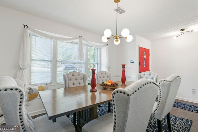 dining room featuring baseboards, wood finished floors, visible vents, and an inviting chandelier