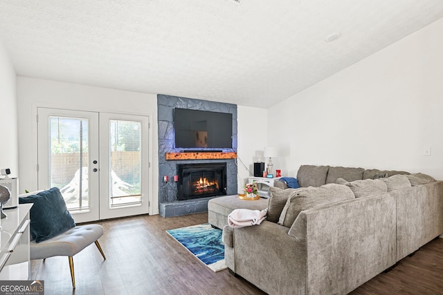 living room featuring a large fireplace, a textured ceiling, dark wood-style flooring, and french doors