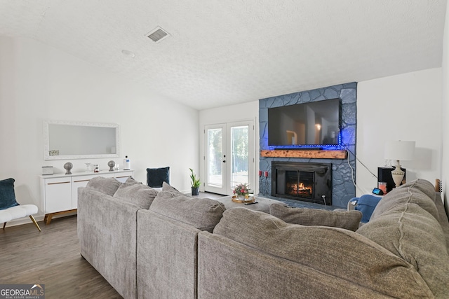 living room with dark wood-style floors, lofted ceiling, visible vents, and a textured ceiling