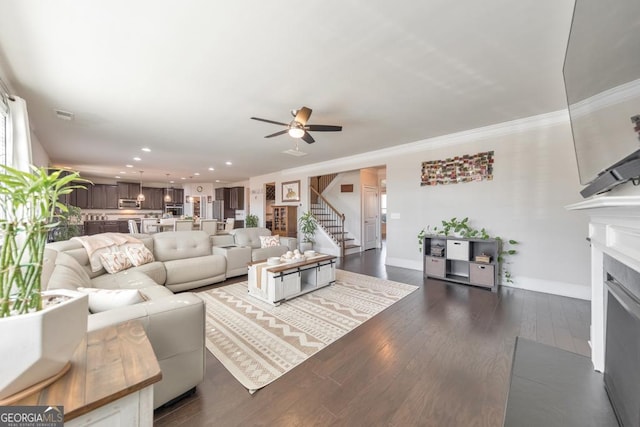 living room with a fireplace with flush hearth, ornamental molding, dark wood finished floors, baseboards, and stairs