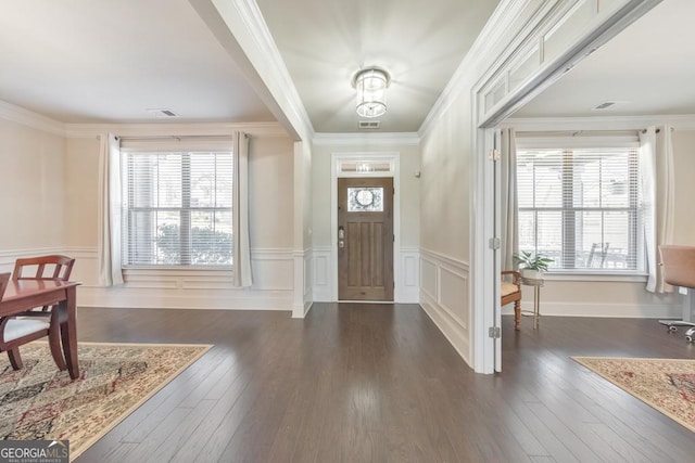 foyer entrance with a wainscoted wall, crown molding, dark wood-style floors, and visible vents