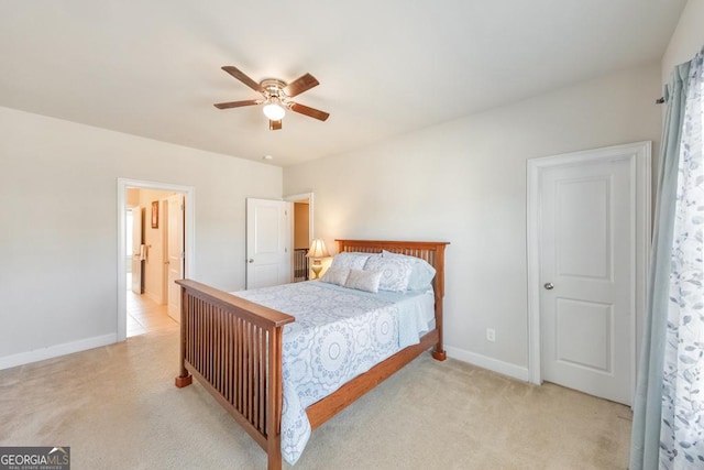 bedroom with ensuite bath, light colored carpet, a ceiling fan, and baseboards