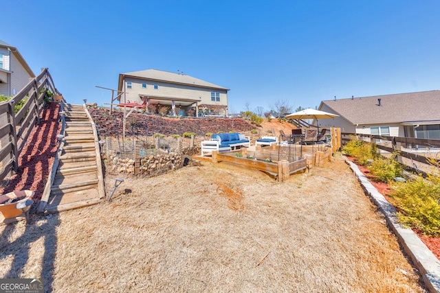 rear view of property with stairway, a garden, and fence