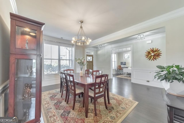 dining area featuring ornamental molding, dark wood-style floors, an inviting chandelier, wainscoting, and a decorative wall