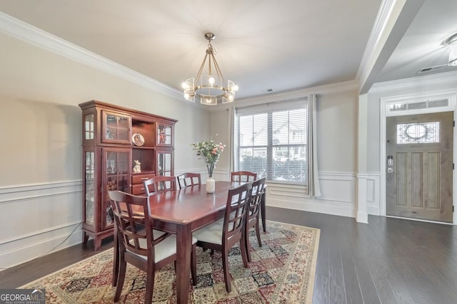 dining space featuring a notable chandelier, wainscoting, dark wood-type flooring, and ornamental molding