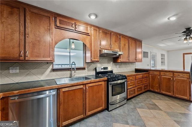 kitchen with brown cabinetry, ceiling fan, appliances with stainless steel finishes, under cabinet range hood, and a sink