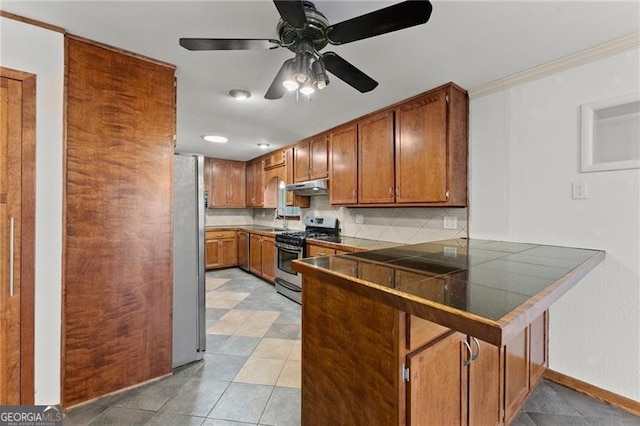 kitchen featuring brown cabinets, decorative backsplash, appliances with stainless steel finishes, a peninsula, and under cabinet range hood