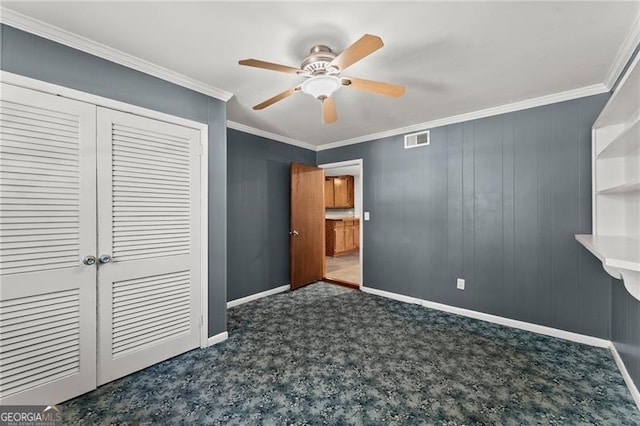 unfurnished bedroom with ornamental molding, a closet, carpet flooring, and visible vents