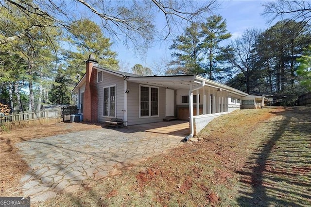 view of side of home with cooling unit, a patio area, fence, and a chimney