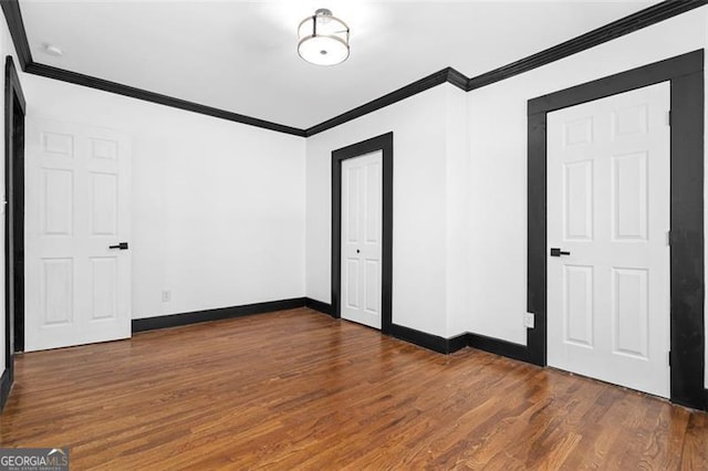 unfurnished bedroom featuring ornamental molding, baseboards, and wood finished floors