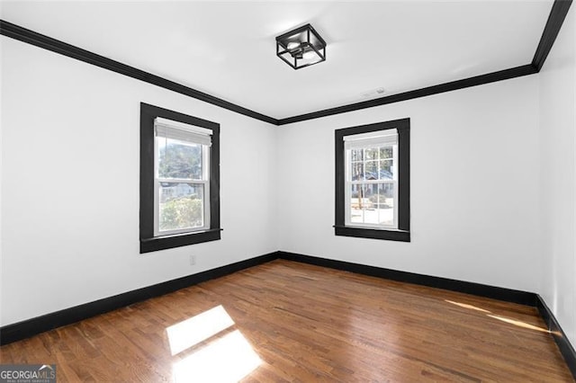 spare room featuring baseboards, crown molding, and wood finished floors