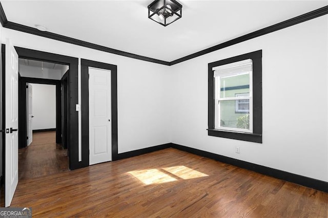 spare room with dark wood-style floors, crown molding, and baseboards