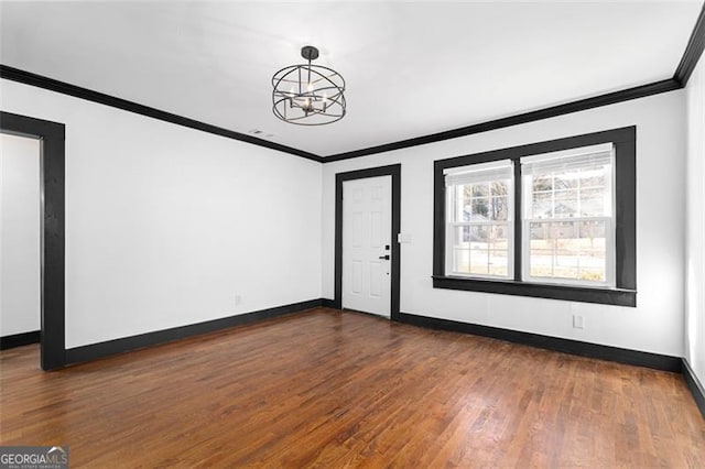 empty room featuring baseboards, dark wood-type flooring, an inviting chandelier, and crown molding