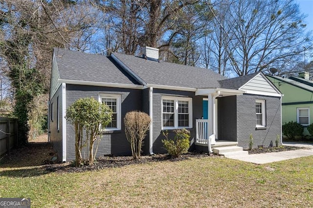 bungalow-style home featuring brick siding, a chimney, a shingled roof, fence, and a front lawn