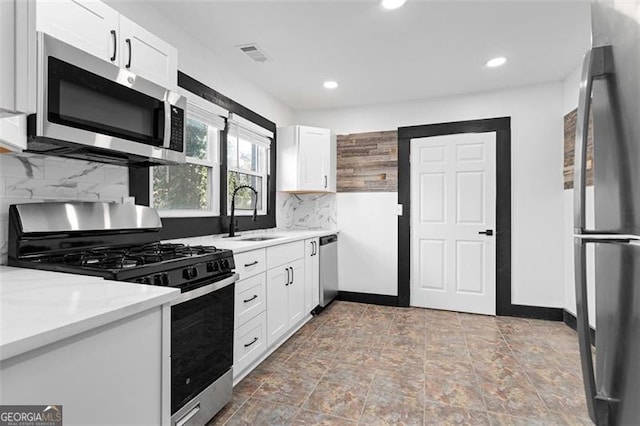 kitchen with stainless steel appliances, tasteful backsplash, light countertops, white cabinetry, and a sink