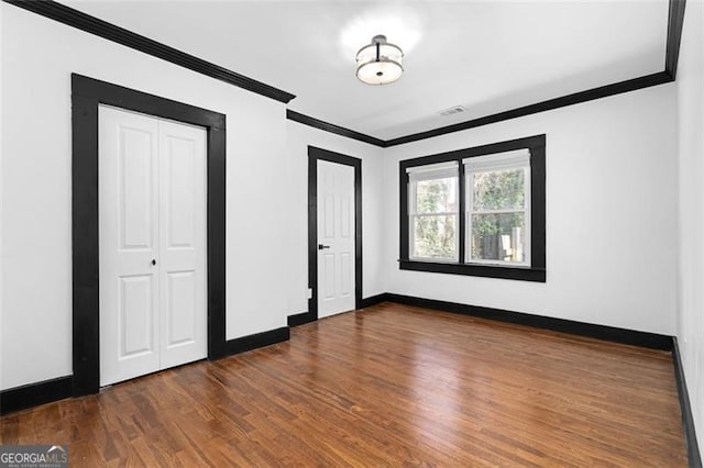 unfurnished bedroom with ornamental molding, baseboards, and wood finished floors