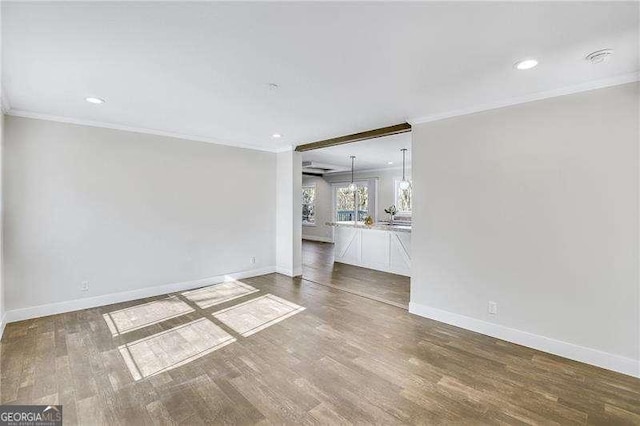 unfurnished living room featuring crown molding, baseboards, and wood finished floors