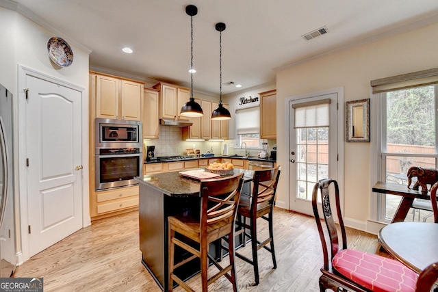 kitchen featuring light wood finished floors, stainless steel appliances, visible vents, backsplash, and light brown cabinetry