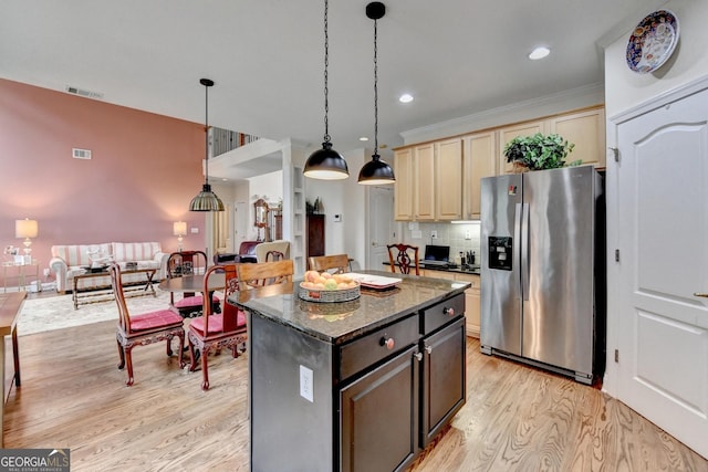 kitchen featuring visible vents, stainless steel refrigerator with ice dispenser, a center island, light wood finished floors, and tasteful backsplash