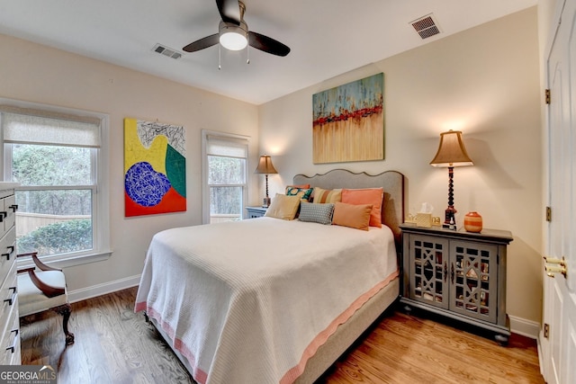 bedroom with baseboards, visible vents, ceiling fan, and wood finished floors