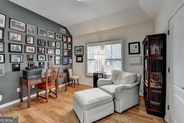 living area featuring light wood-type flooring, baseboards, and vaulted ceiling