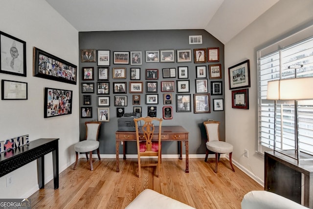 home office with vaulted ceiling, wood finished floors, visible vents, and baseboards