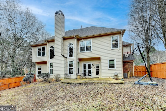 rear view of house featuring a chimney, roof with shingles, fence, central air condition unit, and a patio area