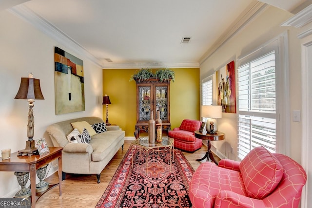 living area with visible vents, crown molding, baseboards, and wood finished floors